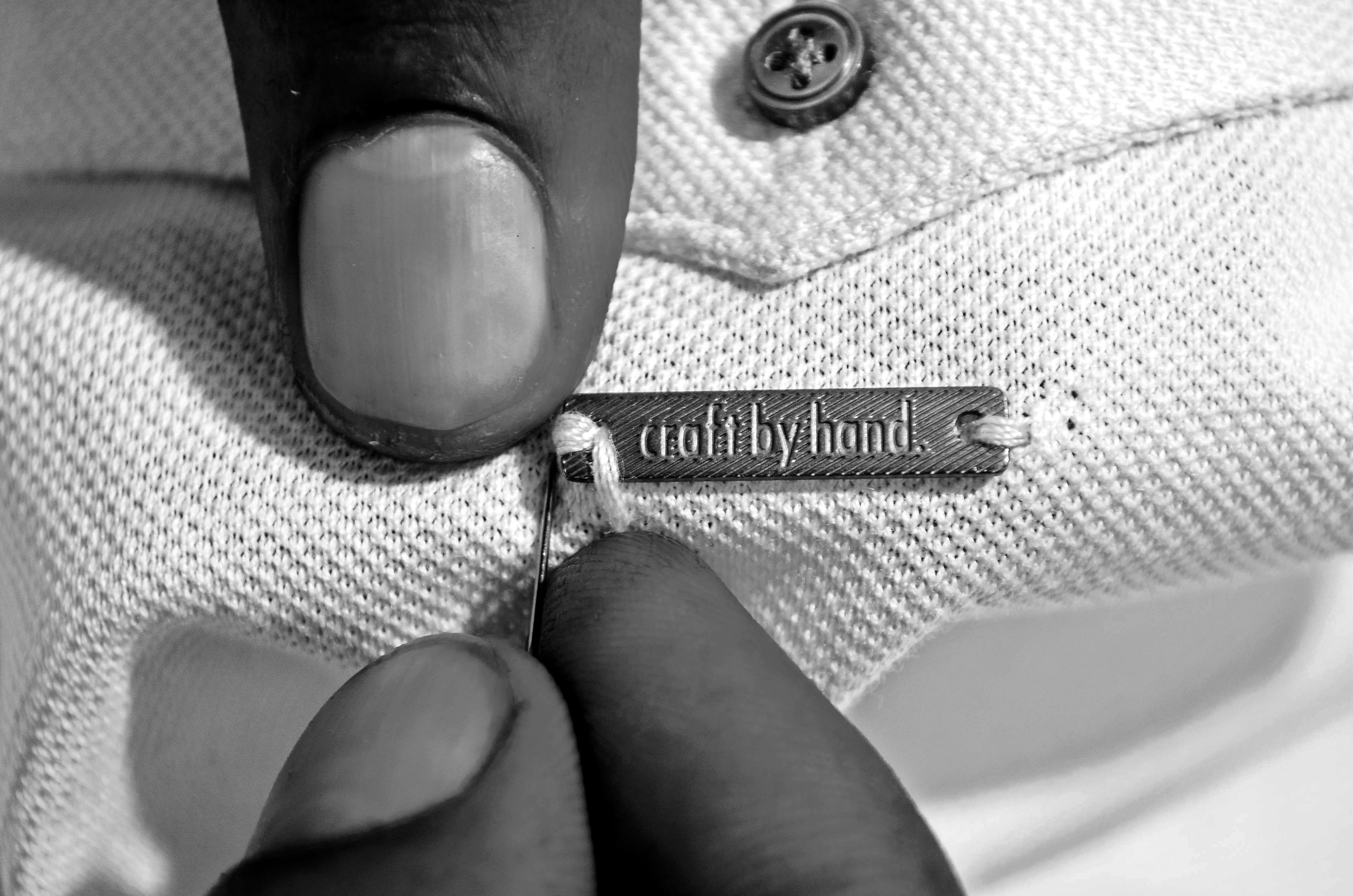Craft by hand label being sewn onto a garment