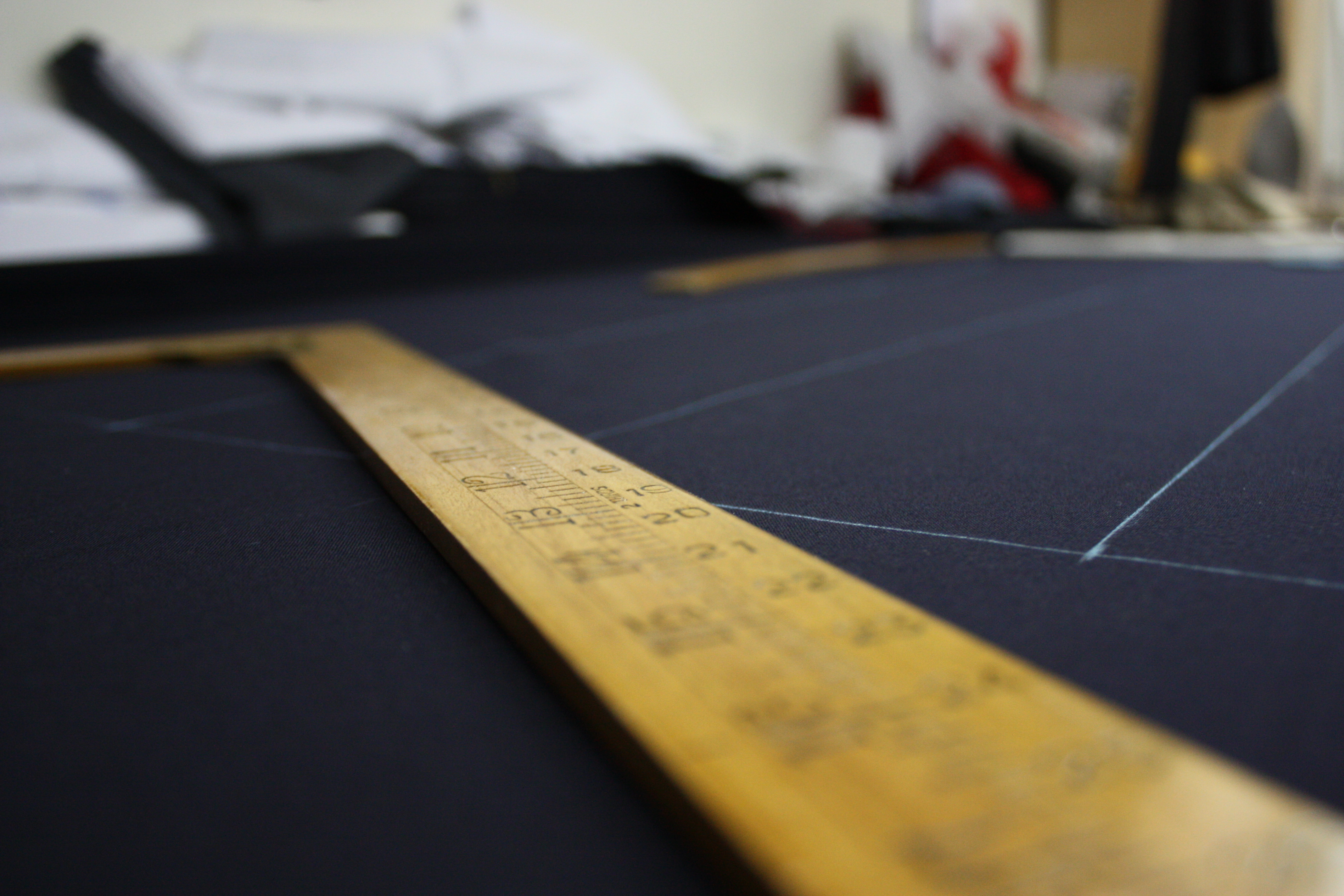 Pattern drafting with ruler on dark suiting cloth